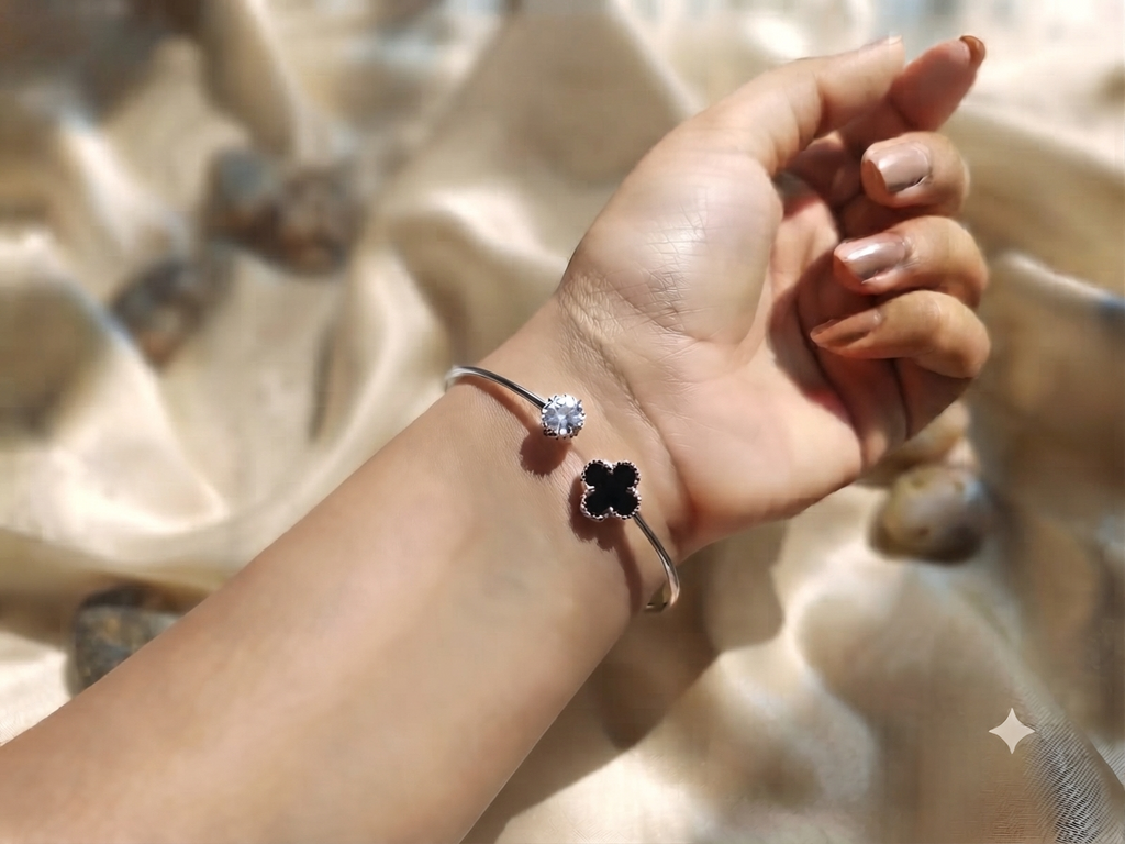 A graceful silver open cuff adorned with a brilliant crystal
